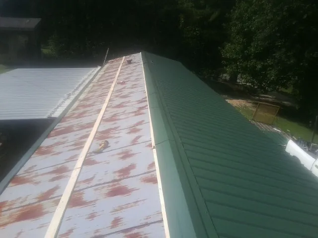 Old rusted panels beside newly installed green metal roofing — Wind Damage Roof Repair by Roofing Brothers in Mirror Lake