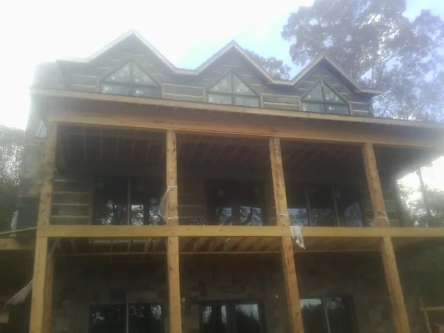 Dormers and porch framing on a large log home under construction — Roof Coating work by our crew in Mirror Lake