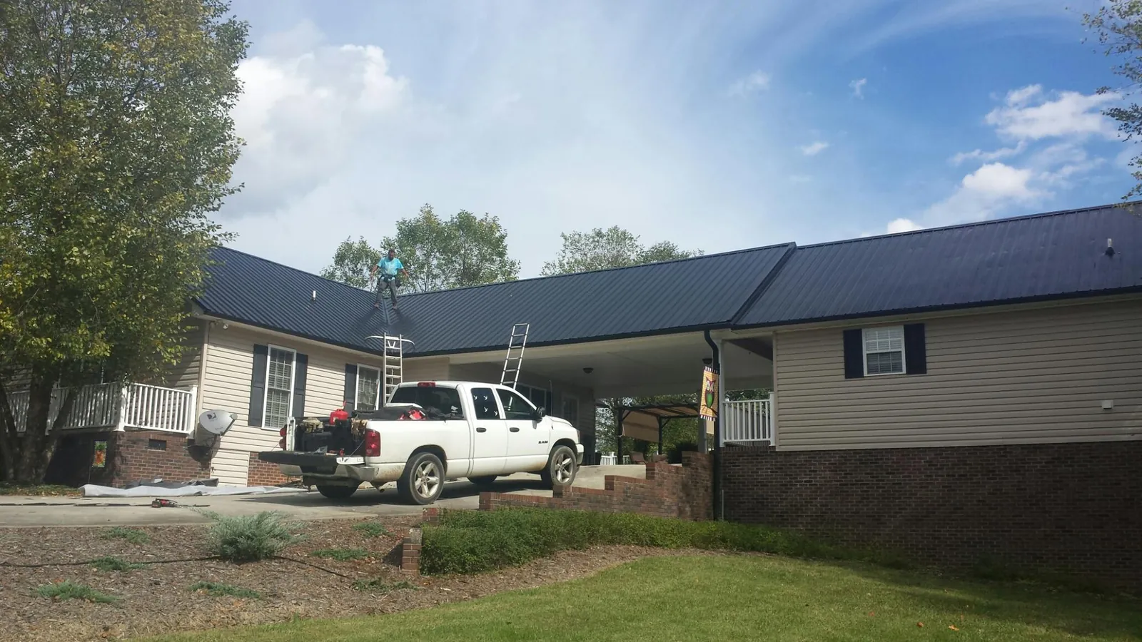 Black metal roof over a home and attached breezeway with ladders set in Mirror Lake