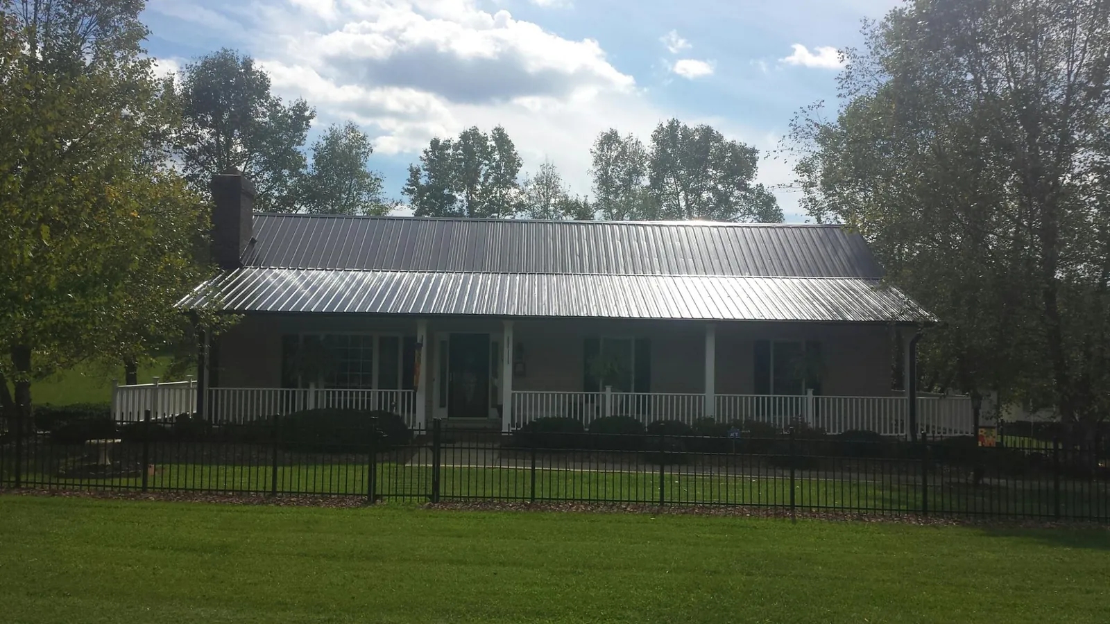 Gray metal roof on a brick ranch with a full width front porch — Gutter Guard Installation work by our crew in Mirror Lake