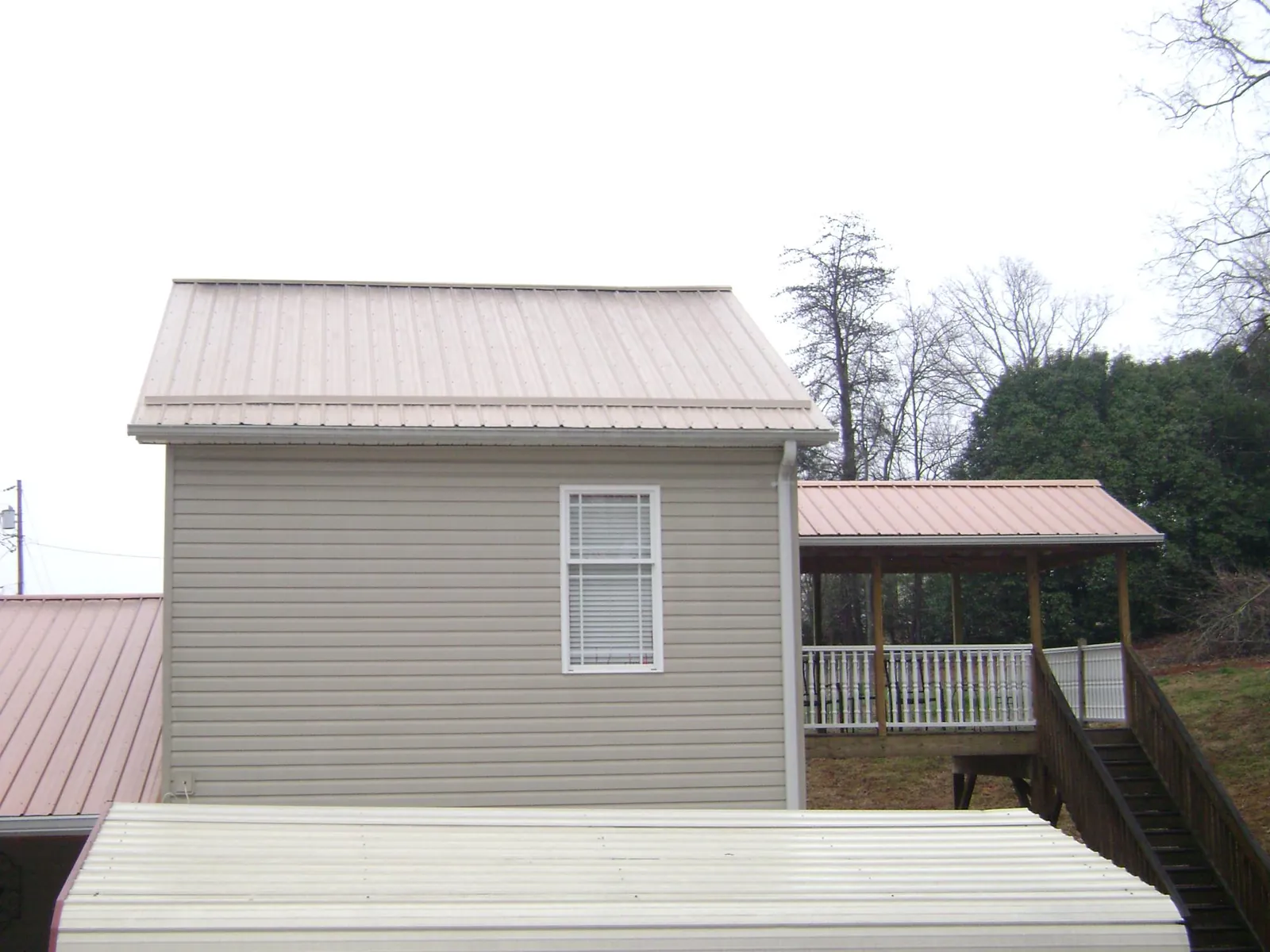 Tan metal roofs on a two story addition and attached porch, from a Roof Replacement job in Mirror Lake