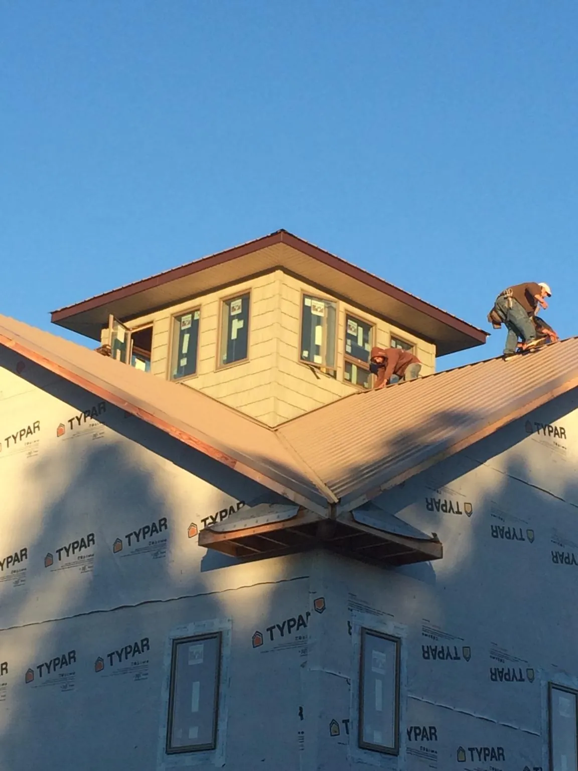 Roofers working around a rooftop cupola on a new metal roof at sunset — Roof Waterproofing in Mirror Lake by Roofing Brothers